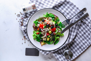 Plate with delicious fresh salad and blank card on light table