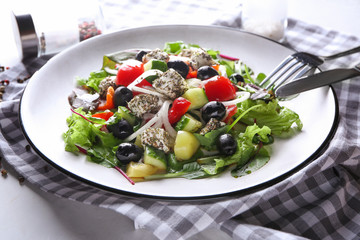 Plate with delicious fresh salad on light table