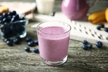 Glass of tasty blueberry smoothie on wooden table