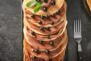 Delicious thin pancakes with berries and chocolate paste on plate