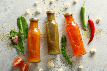 Bottles with tasty sauces on light wooden table