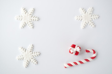 New year or christmas white background with a candy cane, a snowflake, a red box. Top view.