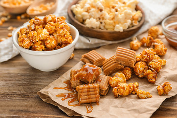 Delicious popcorn, sauce and caramel on wooden background