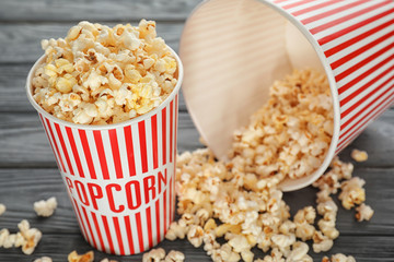Cups with delicious popcorn on wooden background, closeup