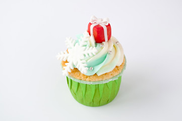 New year or christmas green cupcake with whipped cream, decorated with a snowflake and red box on white background.
