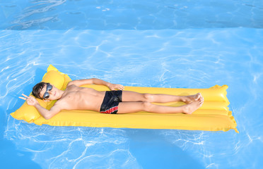 Cute little boy resting on inflatable mattress in swimming pool © Pixel-Shot