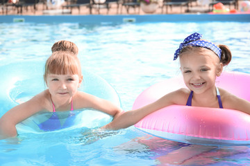 Cute little girls swimming in pool on summer day