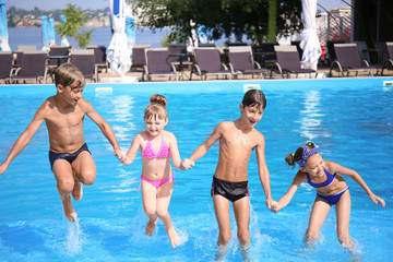 Cute children playing in swimming pool on summer day