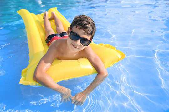 Cute little boy resting on inflatable mattress in swimming pool