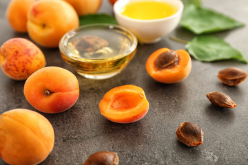 Bowls with essential oil and fresh apricots on table