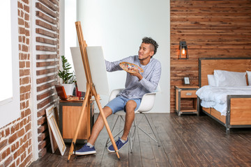 Young African-American artist painting picture at home