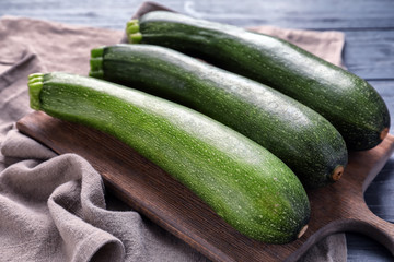 Board with ripe zucchinis on table, closeup