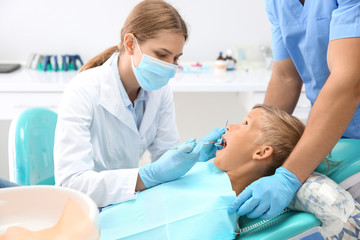 Fototapeta premium Dentist examining little boy's teeth in clinic