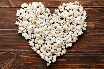 Obraz na płótnie Canvas Heart made of delicious popcorn on wooden table