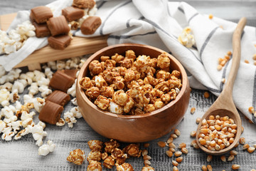 Bowl with delicious caramel popcorn on wooden table