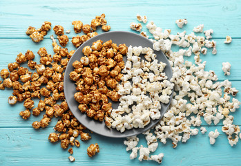 Plate with delicious popcorn on wooden table