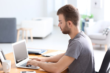 Obraz na płótnie Canvas Handsome man working on laptop in office