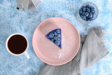 Plate with delicious blueberry cheesecake and cup of coffee on light table