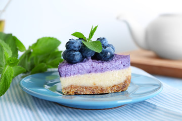 Plate with delicious blueberry cheesecake on table