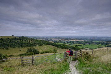 A middle aged male walker with backpack admiring the view from Beacon Hill and Harting Down in the...