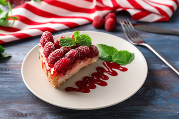 Plate with piece of delicious raspberry cheesecake on wooden table