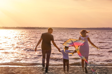 Fototapeta premium Happy family flying kite near river at sunset