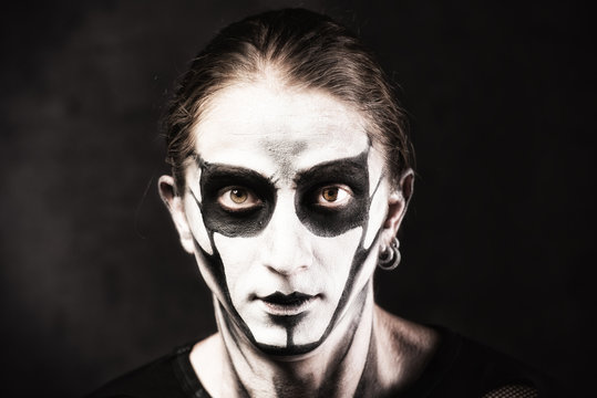 Portrait of man in goth style clothes with scull makeup.