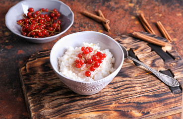 Bowl with delicious rice pudding and currants on board