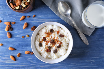 Bowl with delicious rice pudding, nuts and raisins on wooden table