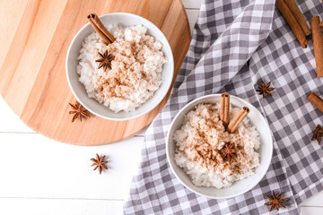 Bowls with delicious rice pudding and cinnamon powder on table