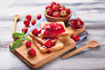 Composition with slices of bread and delicious strawberry jam on wooden table
