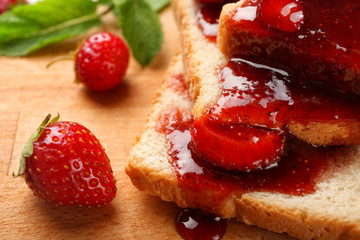 Slices of bread with delicious strawberry jam on board, closeup