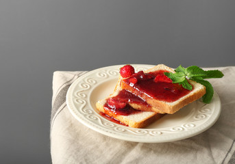 Plate with slices of bread and delicious strawberry on table against grey background