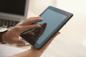 Young freelancer working on tablet computer at home, closeup