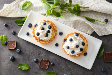 Plate with delicious blueberry tarts on grey table