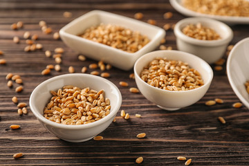 Bowls with raw wheat on wooden table
