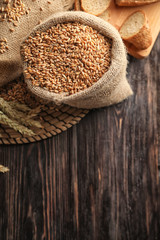 Bag with raw wheat on wooden table