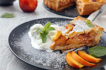 Piece of tasty homemade peach pie and ice-cream on plate, closeup
