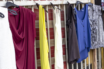 Colorful dresses hanged on metal bars that are ready to be sold near street