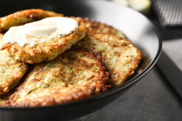 Plate with zucchini pancakes and sauce on table, closeup
