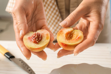 Obraz na płótnie Canvas Woman holding cut peach, closeup