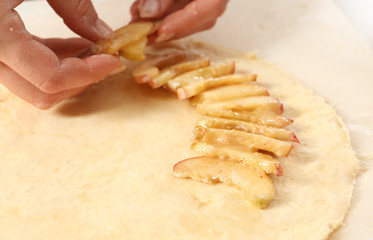 Woman preparing peach galette on table, closeup