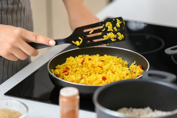Woman cooking rice on stove in kitchen, closeup