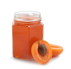 Glass jar with tasty apricot jam on white background