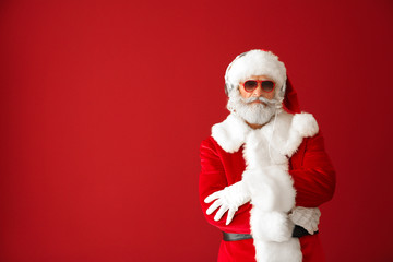 Fototapeta na wymiar Portrait of cool Santa Claus listening to music on color background