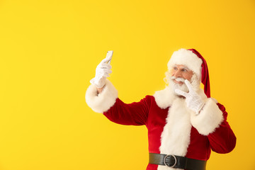 Fototapeta na wymiar Santa Claus taking selfie on color background