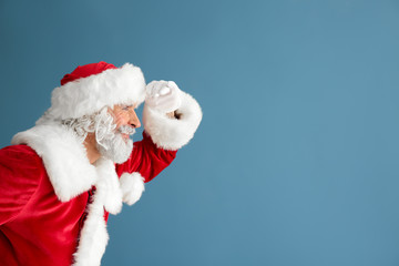 Fototapeta na wymiar Portrait of Santa Claus looking far away on color background