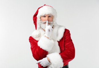 Portrait of Santa Claus showing "silence" gesture on white background