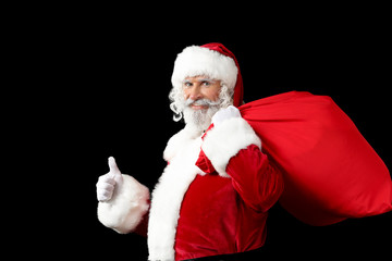 Fototapeta na wymiar Portrait of Santa Claus with bag full of gifts on dark background