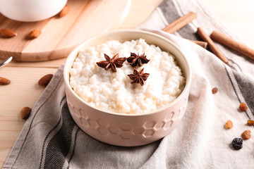 Delicious rice pudding with anise stars in bowl on table